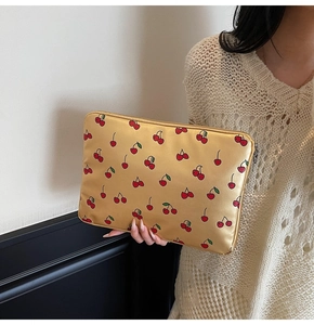 Detailansicht der goldfarbenen Laptoptasche mit Kirschmuster und Metallreißverschluss
