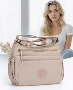 Detail of a beige nylon crossbody bag featuring multi-pocket storage and round logo