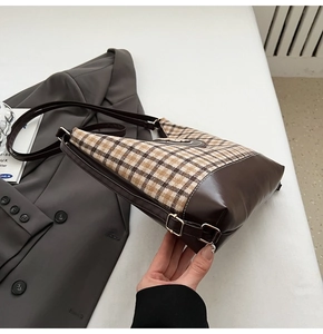Detail of vintage brown plaid tote bag with side metal buckle on grey blazer background
