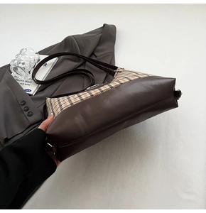 Close-up of vintage brown leather and plaid fabric patchwork tote bag on grey blazer