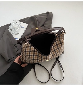 Detailed view of large plaid tote bag with brown leather straps on a grey blazer suit