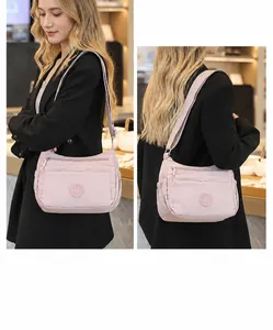 Detail view of pink nylon crossbody bag with multi-zipper pockets and wide strap