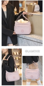 Detailed look at light pink nylon shoulder bag with multi-zipper layers and wide strap