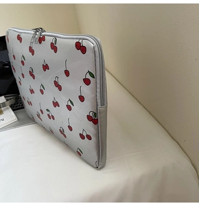Nahaufnahme einer silbergrauen Laptoptasche mit Kirschmustern und Doppelreißverschluss