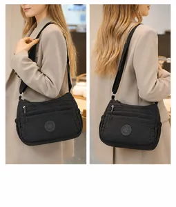 Detail of black nylon multi-zipper crossbody bag showing front pocket and brand logo patch