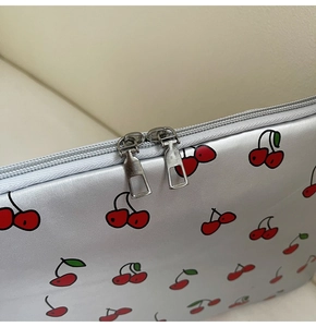 Detailaufnahme der silbernen Laptoptasche mit roten Kirschmotiven und Doppelreißverschluss