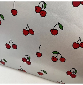 Detailansicht der silbernen PU-Handtasche mit lebhaften roten Kirschdrucken und Textur