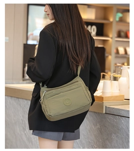Adjustable olive green nylon crossbody bag shown from a side view on a model