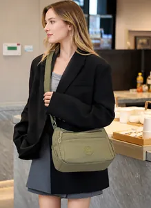 Detail of olive green nylon crossbody bag with adjustable strap and multi-zipper pockets