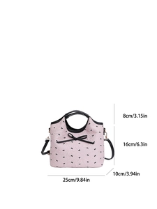 Sac à bandoulière rose avec imprimés nœuds noirs et guide des tailles sur fond blanc