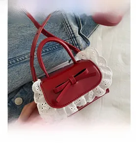 Détail du mini sac en similicuir rouge avec bordure en dentelle blanche et noeud