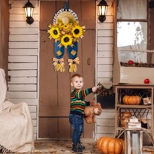 Dettaglio di uno spaventapasseri decorativo con girasoli e denim su un portico in legno
