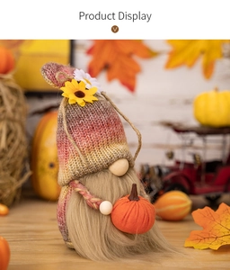 Knitted harvest gnome holding pumpkin with sunflower accent in fall decor setting