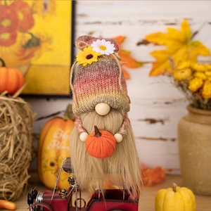 Detailed view of an autumn gnome with shell knit hat holding a pumpkin on a red vintage cart