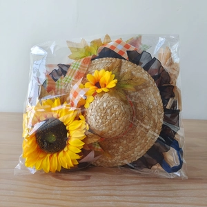 Dettaglio cappello decorativo in paglia con girasoli, foglie d'acero e nastro a quadretti