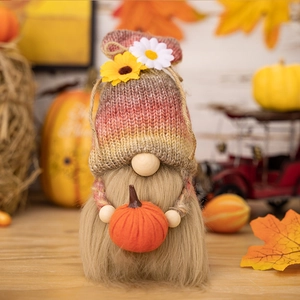 Macro detail of gnome plush featuring knitted hat with sunflower and holding a pumpkin