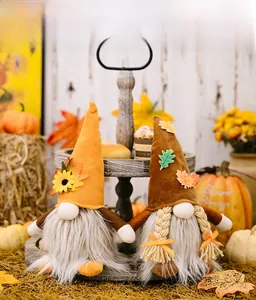 Detail of festive Thanksgiving gnomes with maple leaf hats and glowing lights on wood