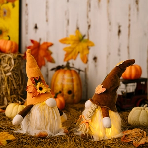 Close-up of glowing Thanksgiving gnomes with LED lights, maple leaf hats and sunflowers