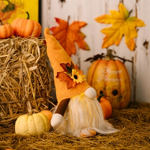 Close-up of Thanksgiving gnome with maple leaf hat and sunflowers on wooden background