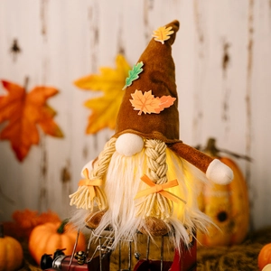 Close-up of lighted Thanksgiving gnome sitting on red truck with autumn maple leaf details