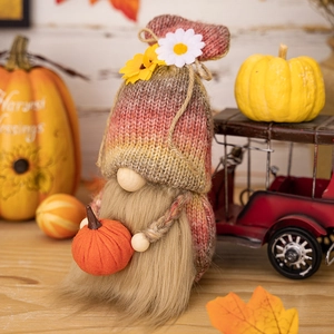 Knitted fall gnome with colorful gradient hat holding pumpkin for harvest decoration