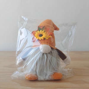 Close-up of Thanksgiving gnome plush in packaging featuring autumn sunflower and maple leaves