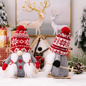Close-up of Christmas gnome plush with knitted snowflake hat and wooden skis on snow