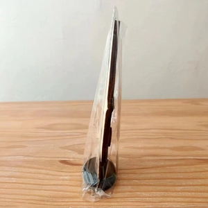 Side view of wooden Halloween ghost gnome decor with round base in plastic packaging