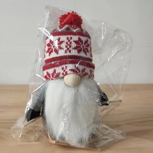 Detail of Christmas gnome figurine with knitted hat and wooden skis in packaging