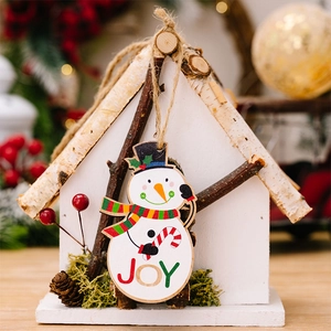 Detail of wooden Christmas house ornament featuring a hand-painted JOY snowman and pine cones