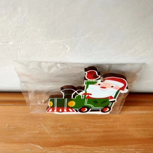 Detailed view of a wooden Santa Claus train ornament in clear protective packaging