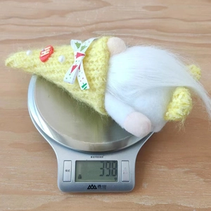 Close-up of yellow knitted Christmas gnome with white beard on an electronic scale
