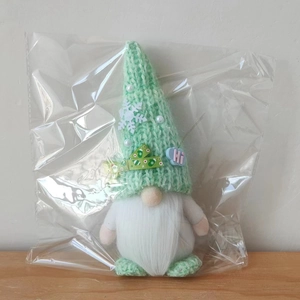 Detail of green knitted Christmas gnome ornament with white snowflake patch and Hi badge