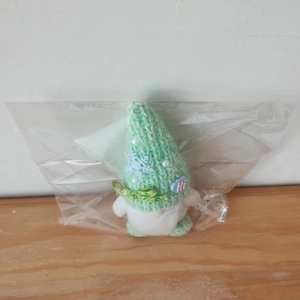Detail of mint green knitted Christmas gnome with snowflake patterns and ribbon bow
