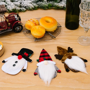 Close-up of three festive Christmas gnome silverware holders on a rustic wooden table