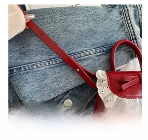 Détail du mini sac en cuir brillant rouge avec dentelle blanche et bandoulière