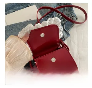 Détail du mini sac en cuir rouge avec bordure en dentelle blanche et boucle aimantée