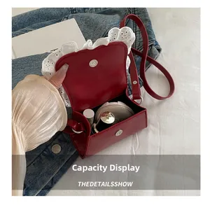 Détail de la capacité interne du sac en cuir rouge avec bordure en dentelle blanche