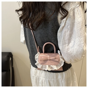 Détail du mini sac en dentelle rose avec nœud décoratif porté par un mannequin