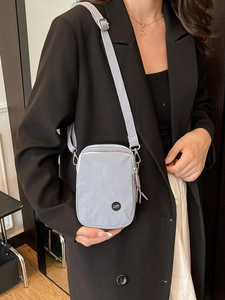 Elegant light gray crossbody bag with adjustable strap and metallic logo detail
