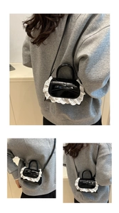 Détail d'un mini sac à main noir brillant avec bordure en dentelle blanche et nœud