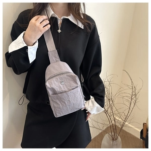 Détail d'un sac bandoulière léger en nylon lavande avec sangle large et logo en métal