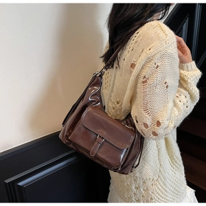 Détail d'un sac cabas marron brillant avec rabat avant porté à l'épaule par un mannequin