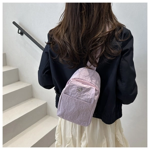 Detail of lavender nylon chest bag with pleated texture and round metallic logo