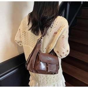 Détail du sac à bandoulière en cuir marron brillant avec boucle en métal et sangle