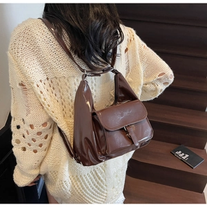 Sac à dos rétro en cuir verni marron café avec bretelles réglables porté par un modèle