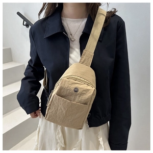 Detail of khaki nylon crossbody bag with adjustable strap and metallic logo on model