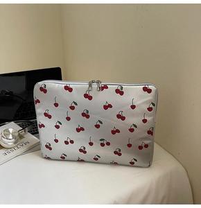 Silver cherry print laptop sleeve with dual zippers on a desk with a laptop and book