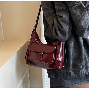 Détail du sac hobo en cuir verni bordeaux avec rabat à boucle et finition brillante