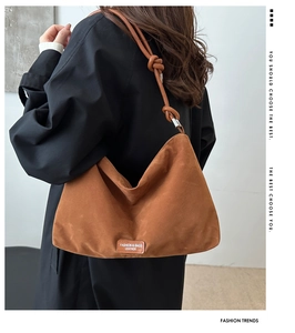 Close-up of brown suede hobo bag with knotted strap detail and metal fashion nameplate